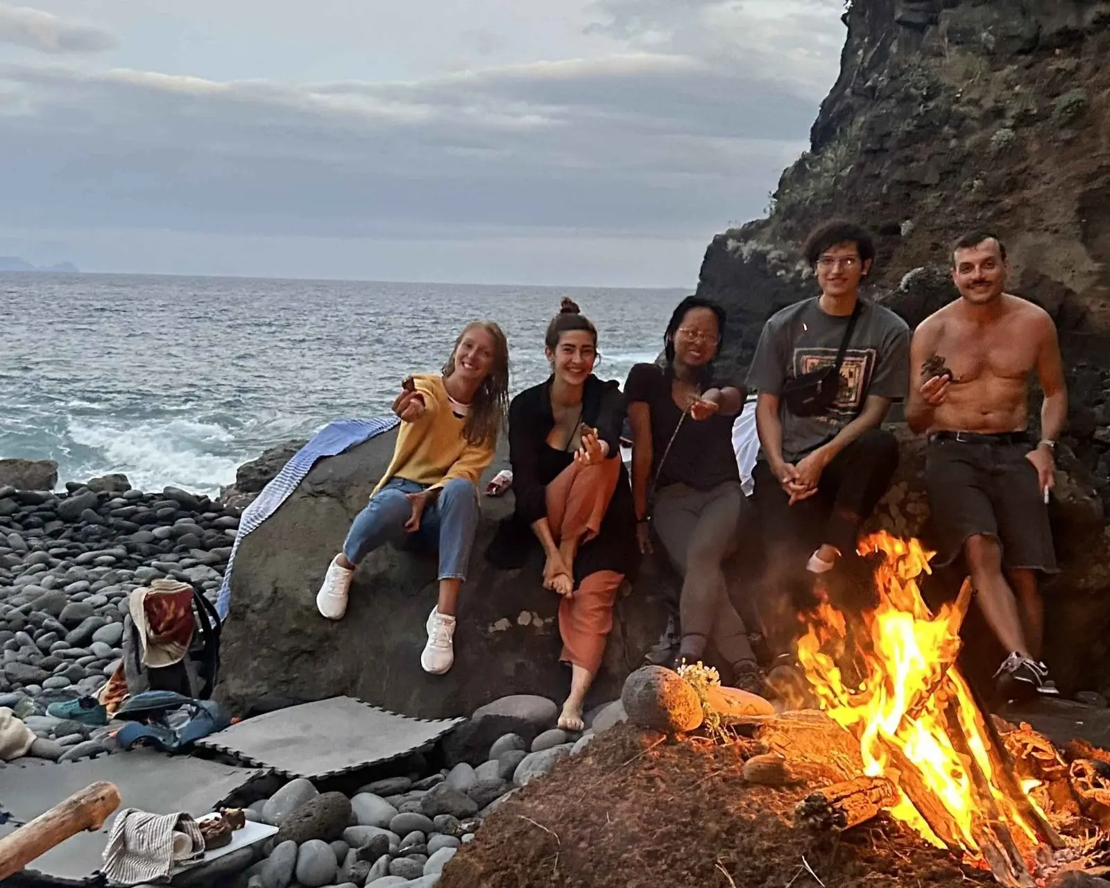 Friends around a bonfire on a pebble beach in Madeira