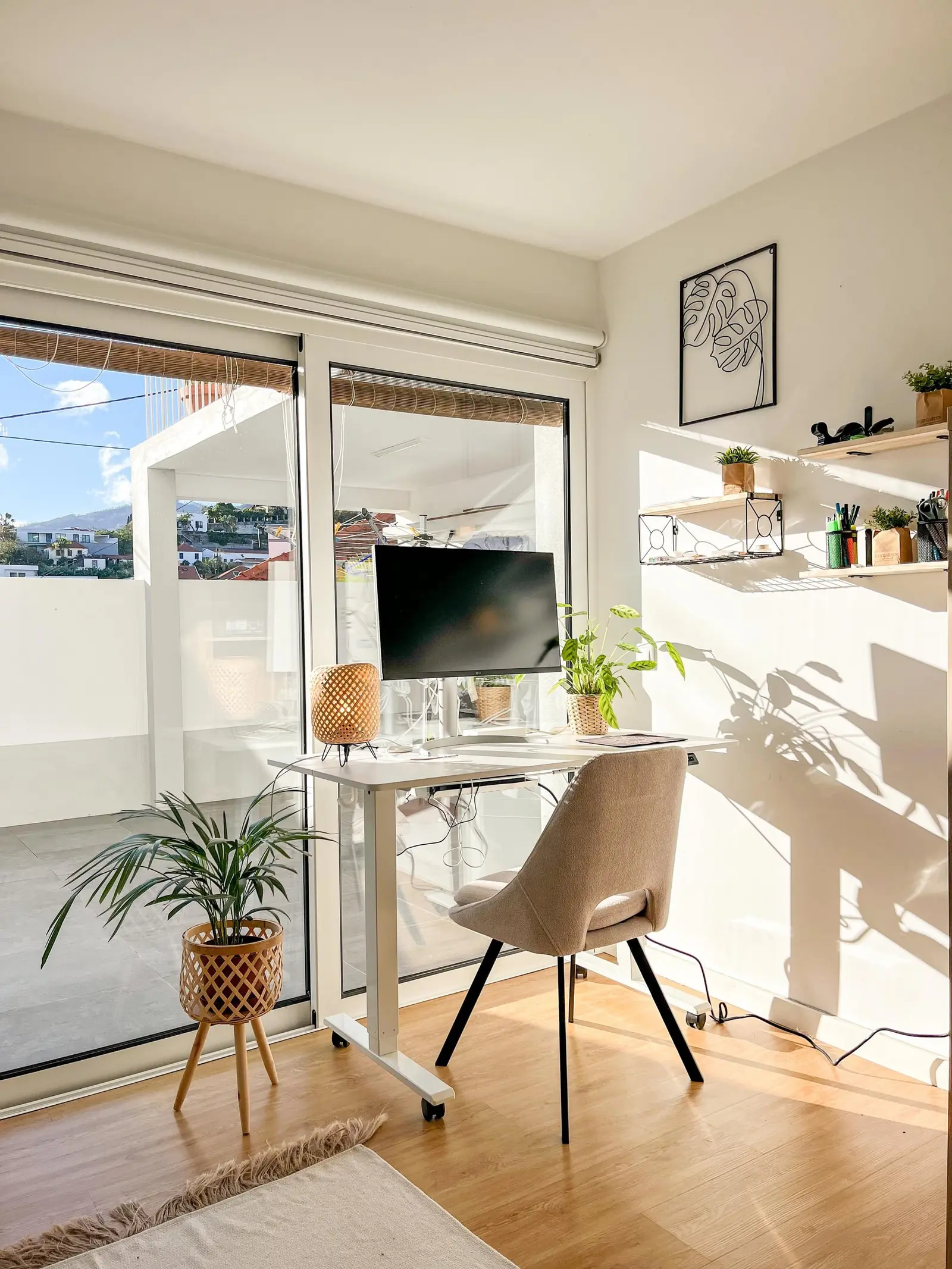 Standing desk with monitor next to sliding doors and a view of the city