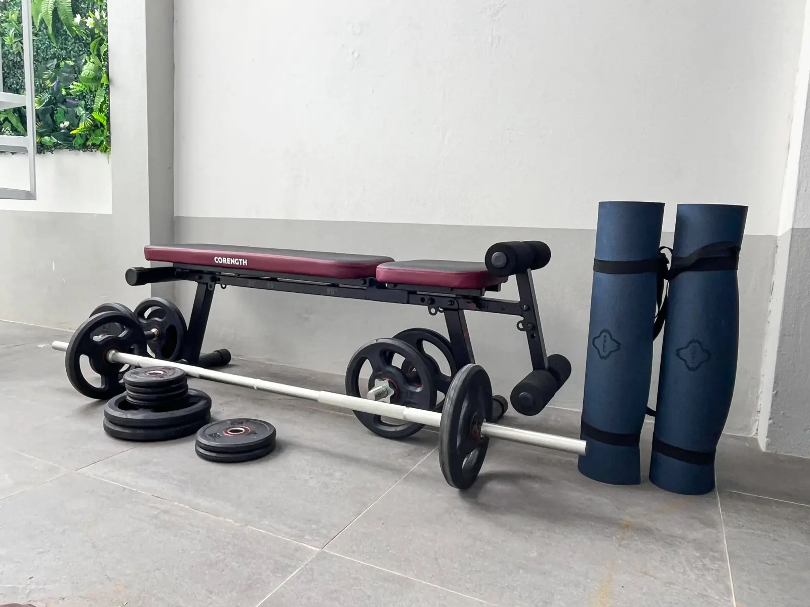 Workout bench, barbell, weight plates and two yoga mats on the rooftop terrace
