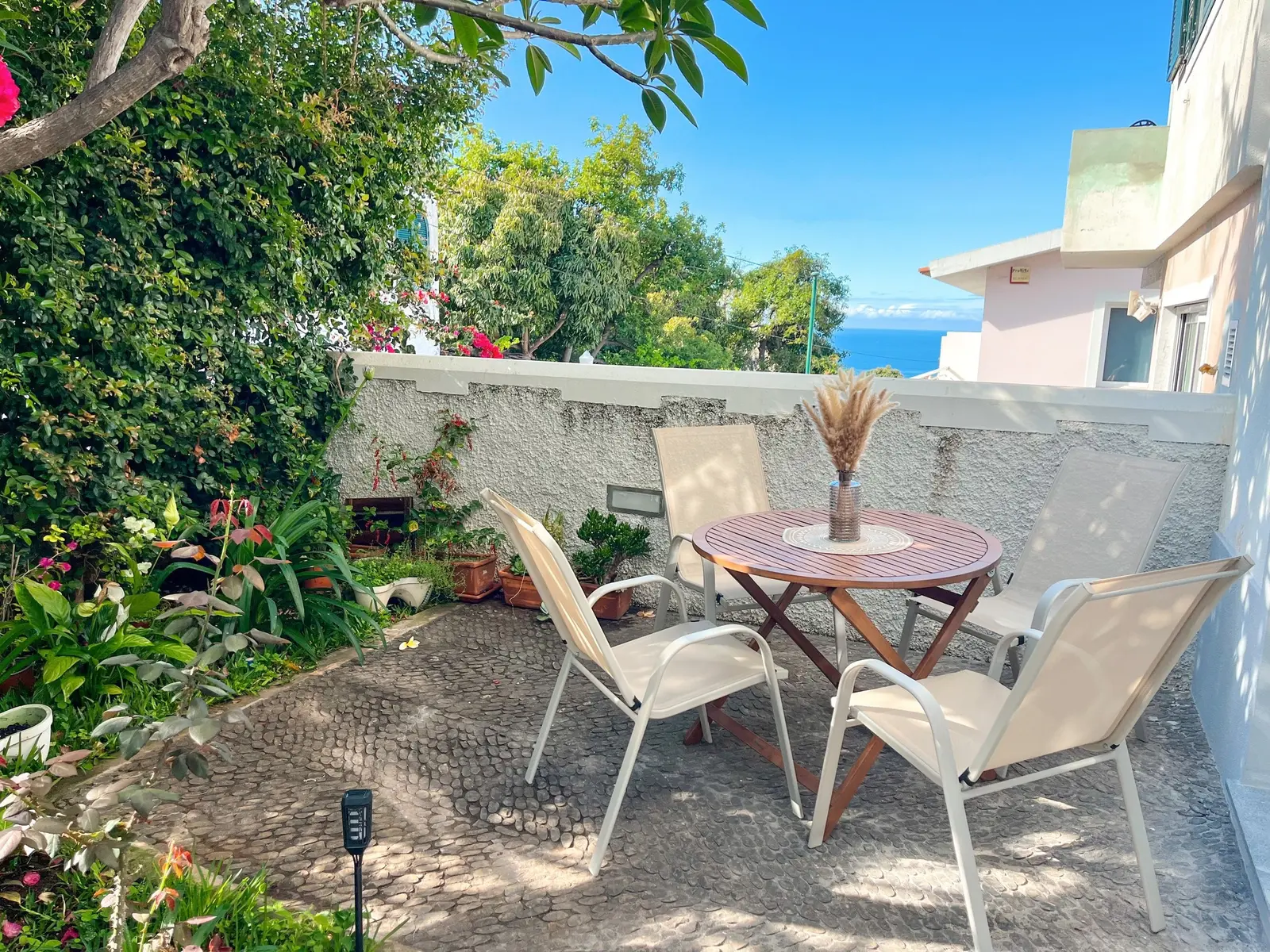 Shaded garden patio with table and chairs surrounded by plants