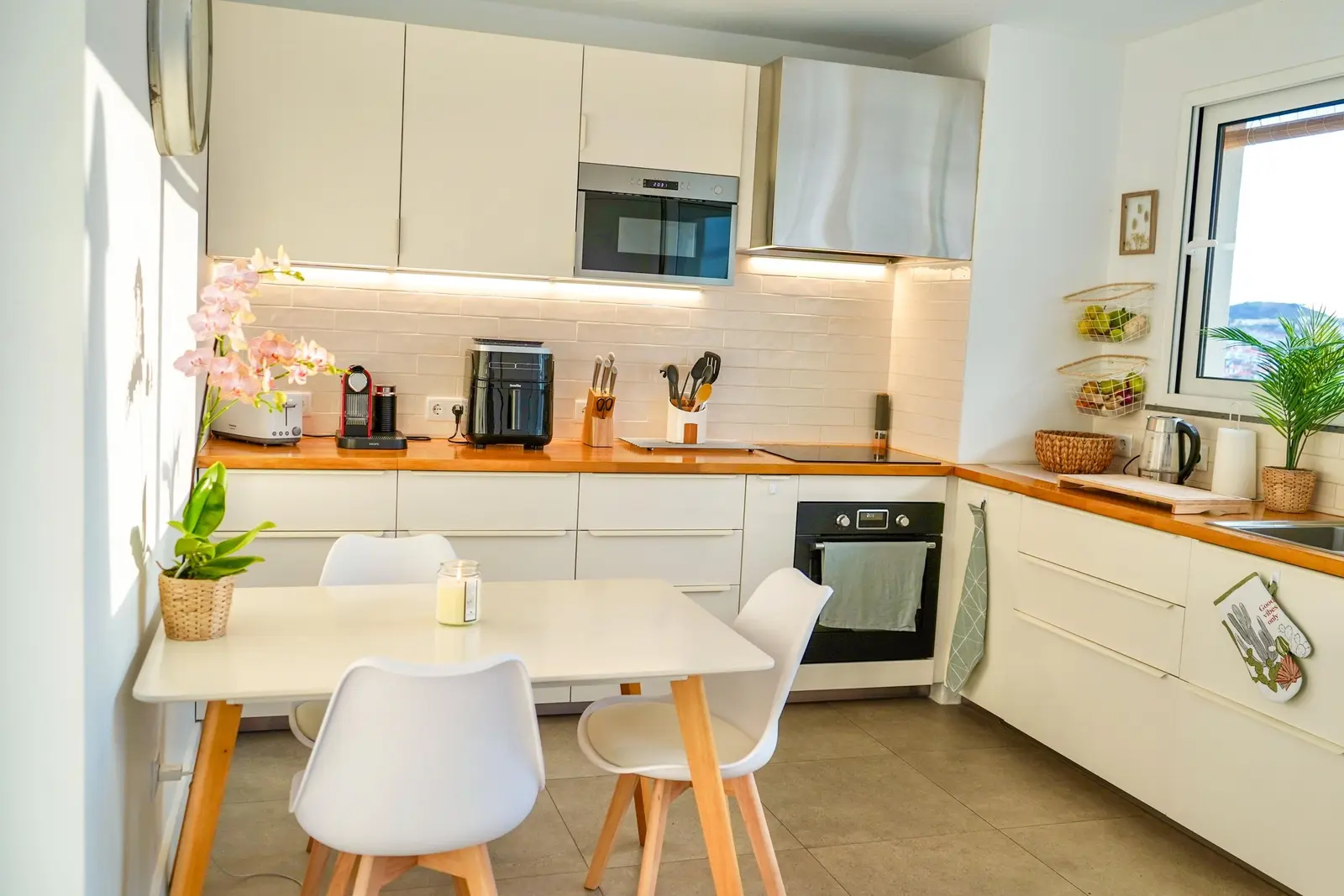 Bright, fully equipped white kitchen with a small dining table
