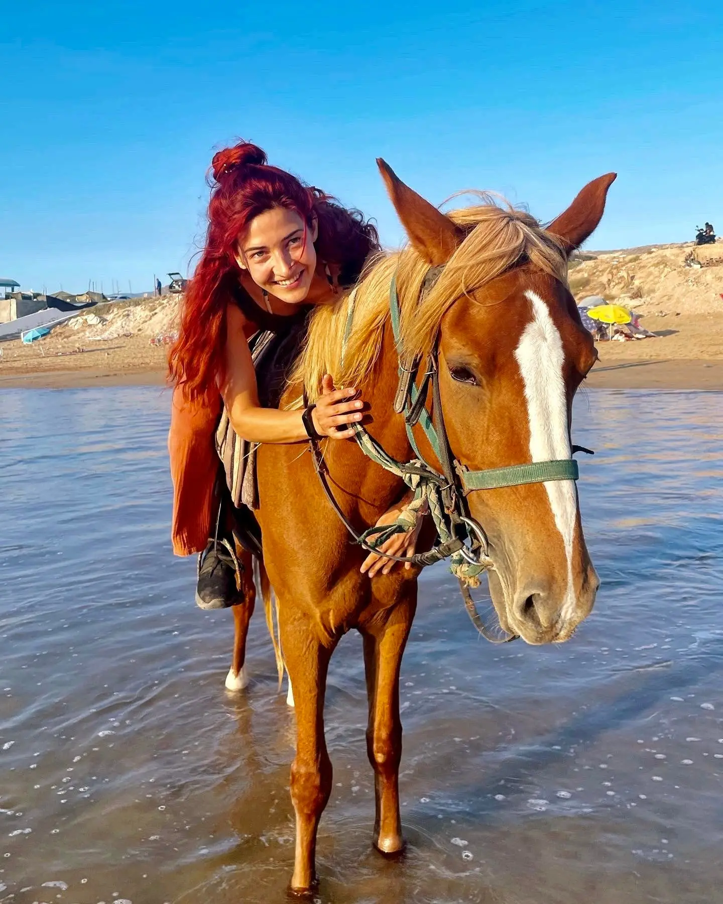 Nina with a horse in the shallow sea on a sunny day