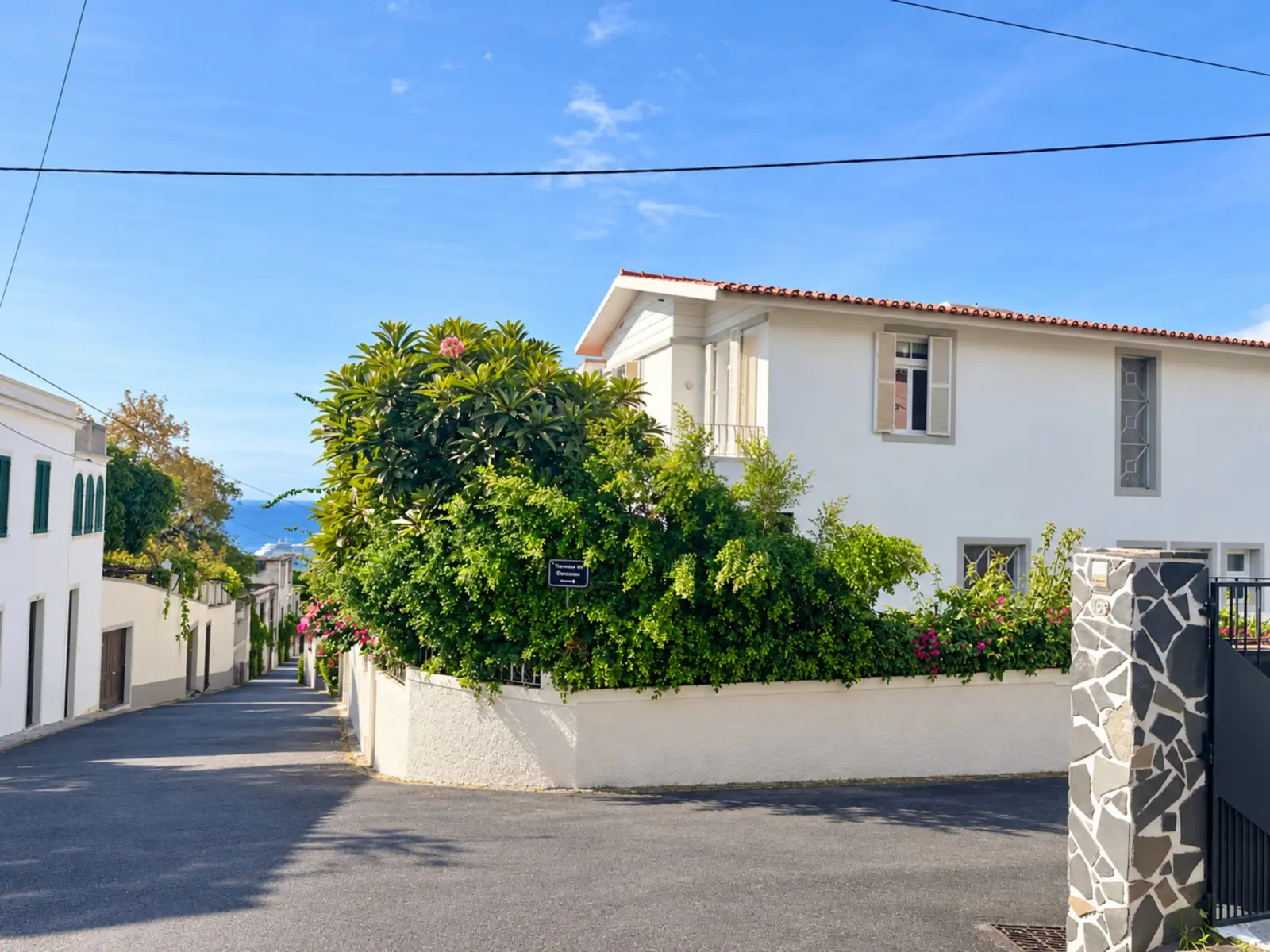 Quiet street in Santa Luzia beside the Luzia House and its flowering garden wall, running down to the sea