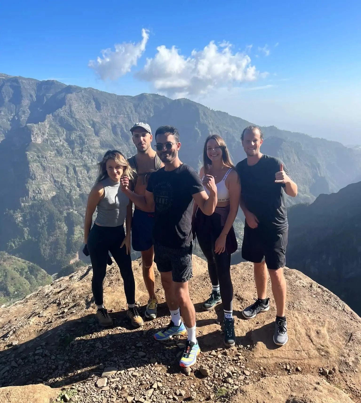 Five hikers on a summit with Madeira's mountain range behind them