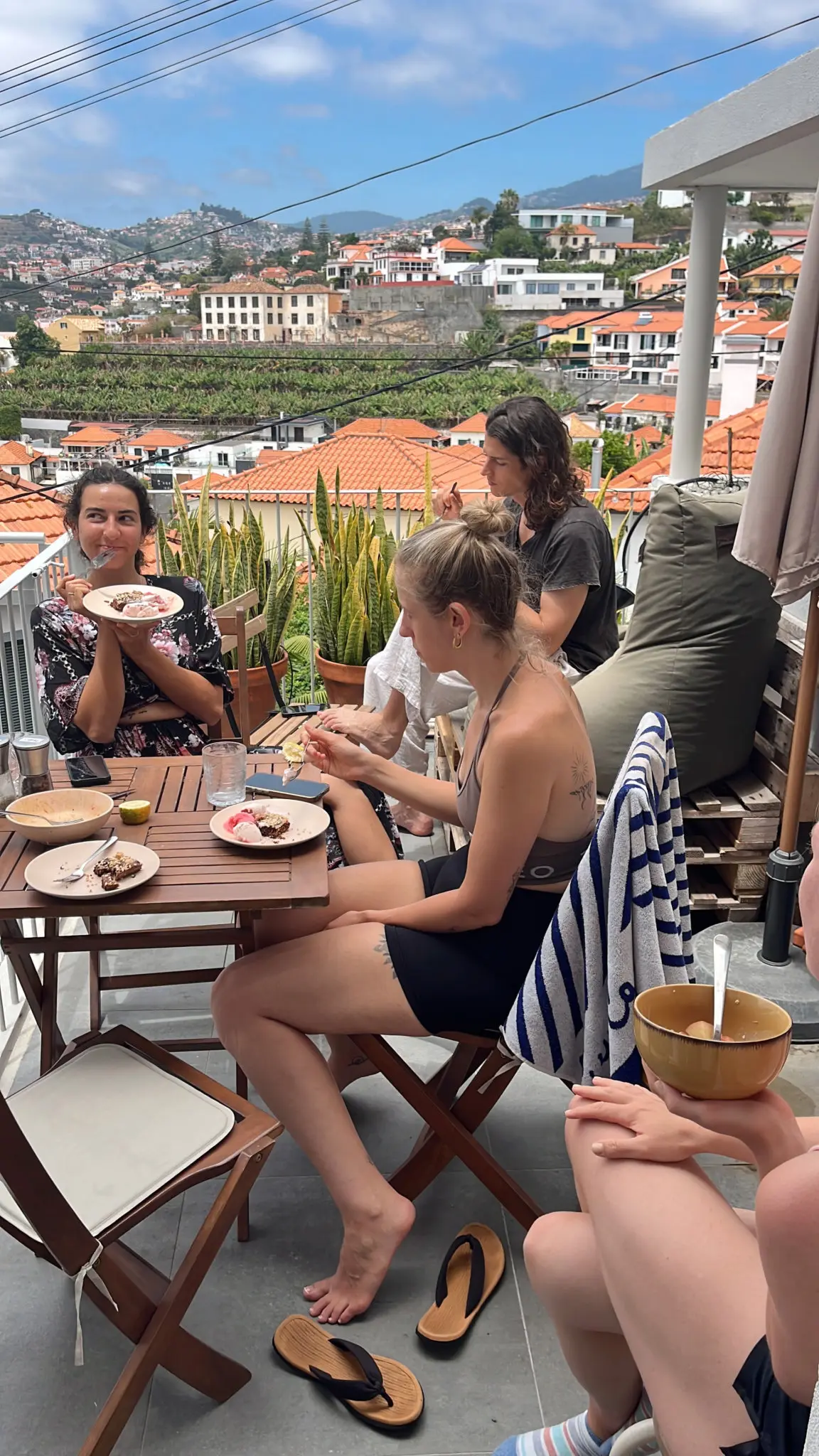 Residents eating lunch together on the sunny terrace, overlooking the red rooftops and banana plantations of Funchal
