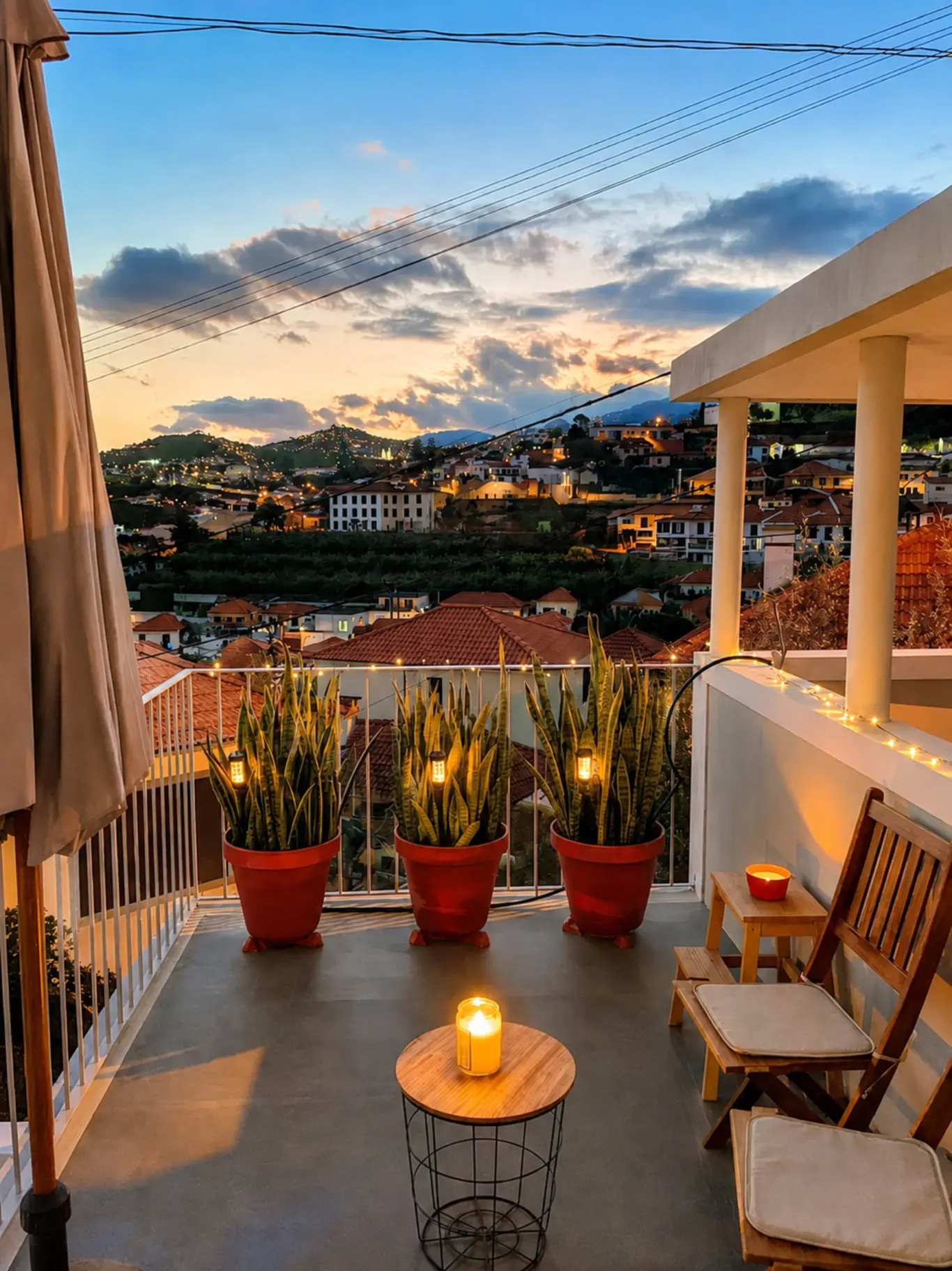 Terrace at dusk with candles, fairy lights and potted plants, looking over the rooftops and hills of Funchal